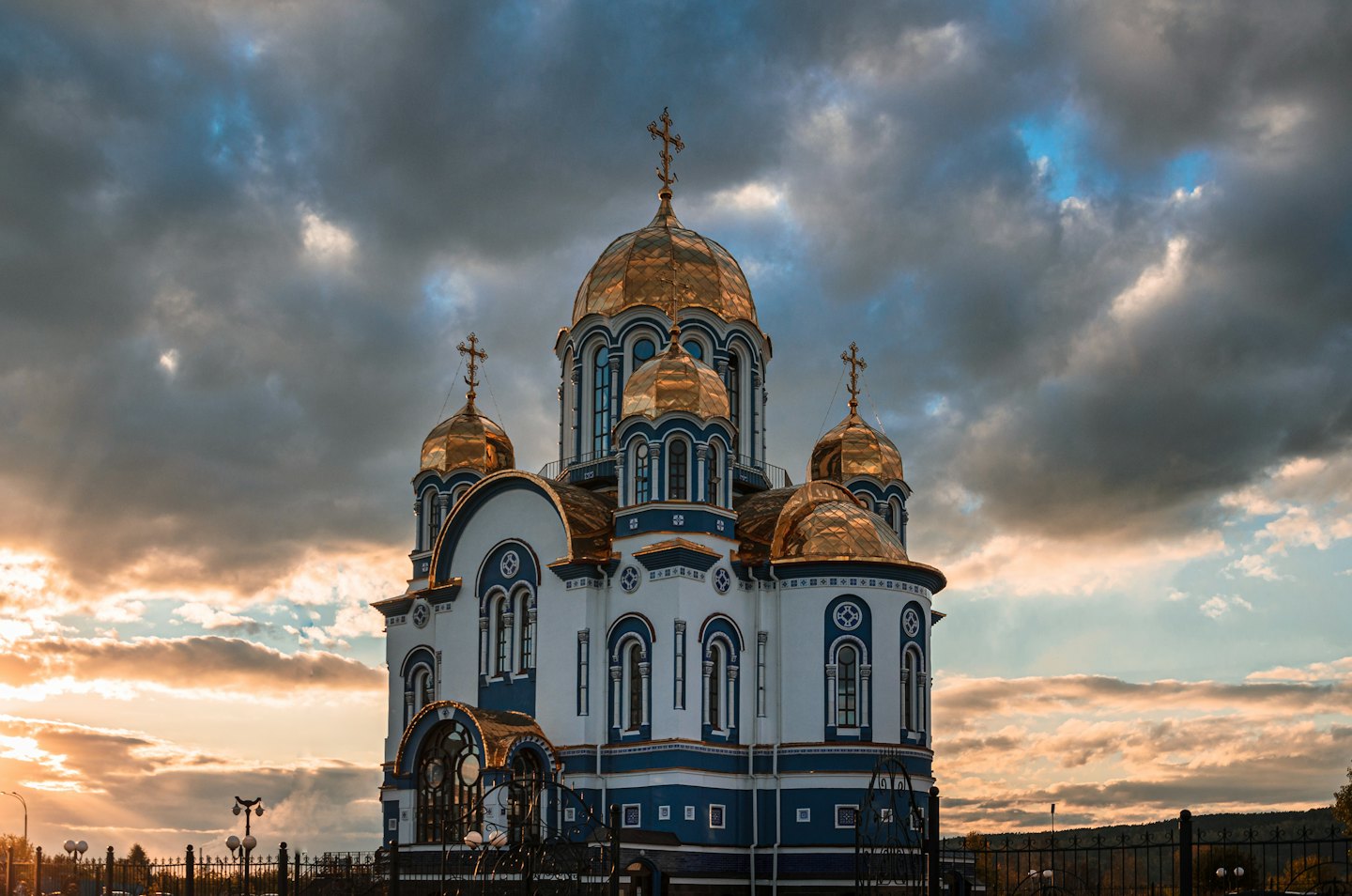 Eastern Orthodox church with golden onion domes under a cloudy sky.